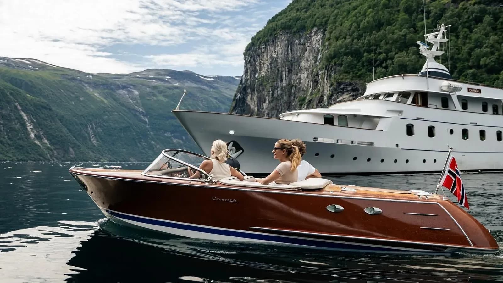 Guests in Chantal’s varnished wooden tender beside the yacht