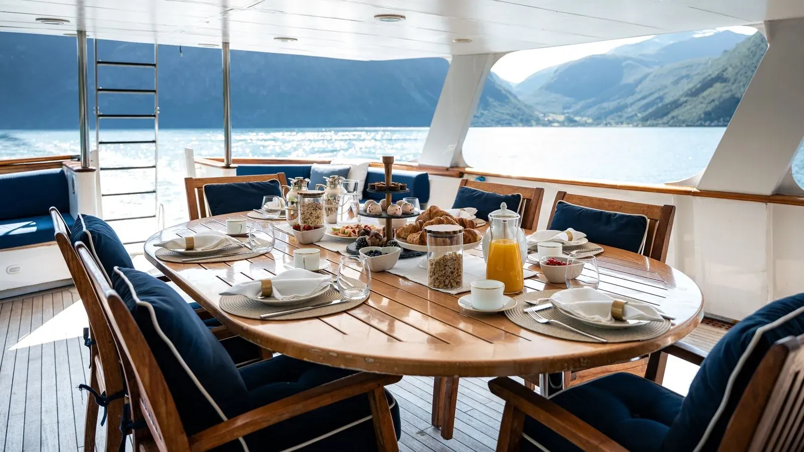 Breakfast laid out on the aft deck with a fjord view