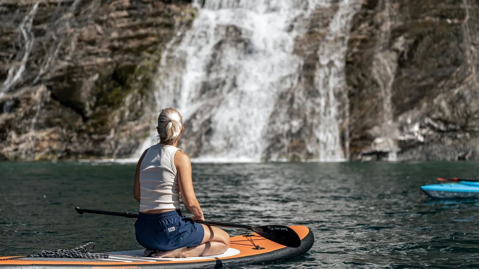Guest paddleboarding in front of a waterfall