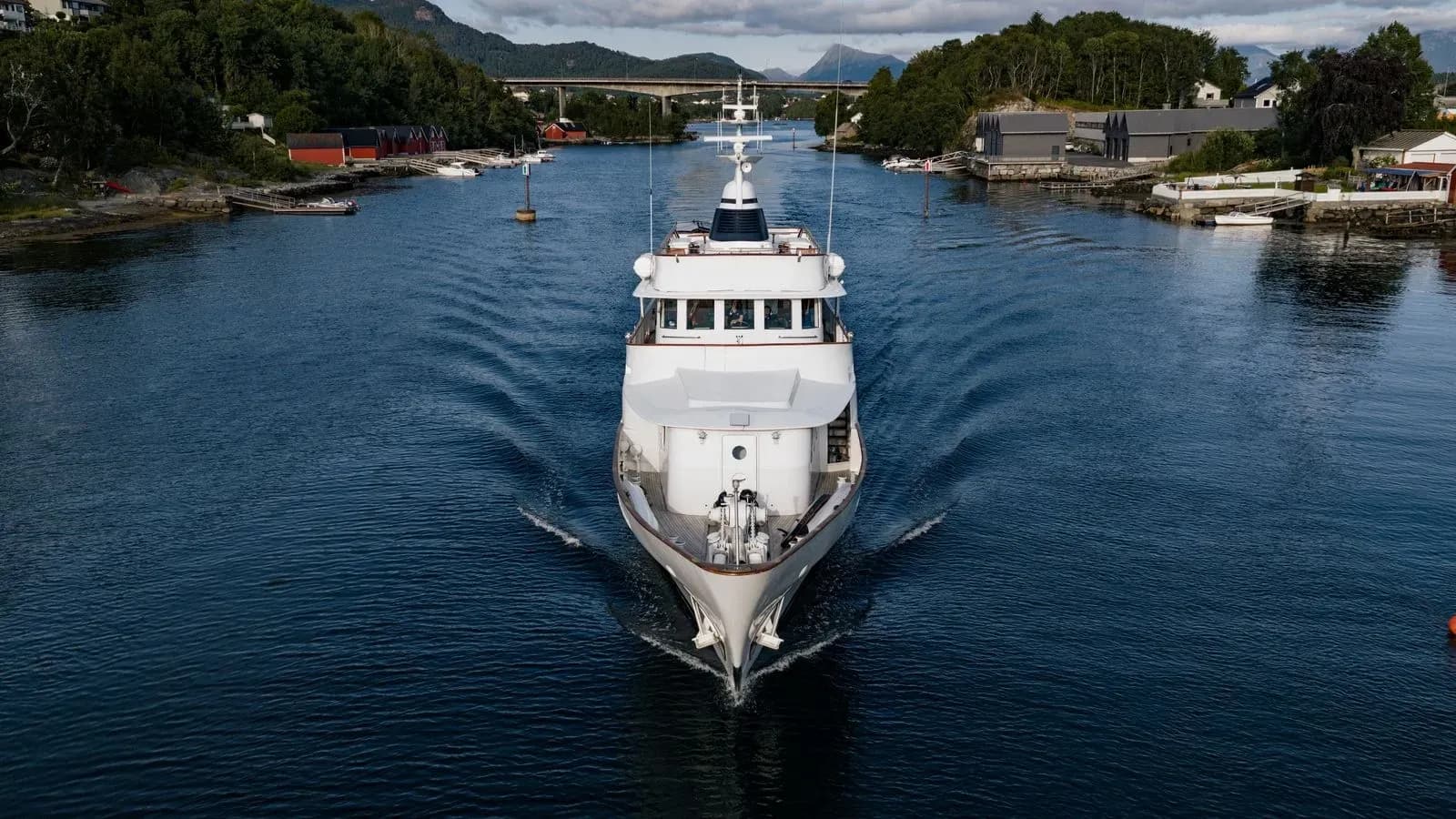 Bow-on aerial view of Chantal underway near a coastal village