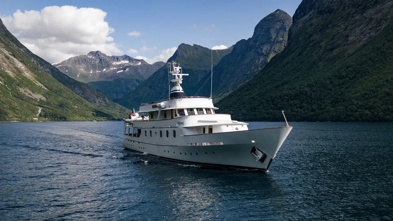 Chantal underway against steep green fjord mountains