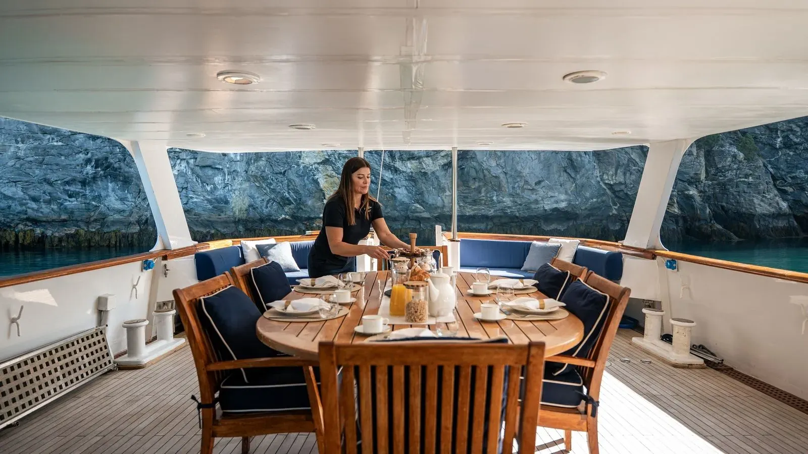 Crew setting the breakfast table on Chantal’s sheltered aft deck